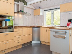 A kitchen with wooden cabinets, a stainless steel dishwasher, and a built-in oven. - 6 Person Holiday Home in Knebel (Knebel)