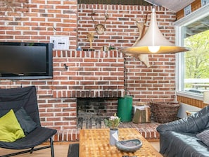A living room with a brick fireplace, a television, and seating arrangements.