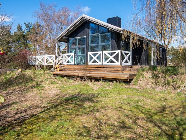 A modern cabin with a wooden deck, large windows, and a chimney.