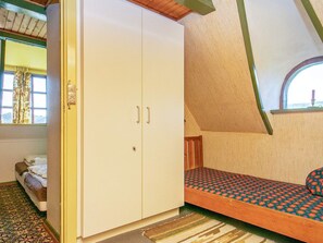 Un dormitorio con cama, armario y ventana con cortinas.