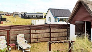 A fenced outdoor area with two lounge chairs, a small table, and a thatched-roof structure. - 5 Person Holiday Home in Ulfborg (Ulfborg)