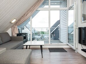 Un dormitorio estilo loft moderno con un tragaluz grande, un sofá, una mesa de comedor y un televisor.