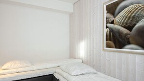 Een kleine kamer met een enkel bed, een houten wand en een lijst met schelpen.