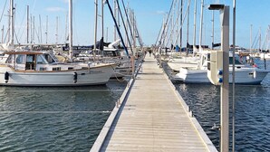Een jachthaven met meerdere boten afgemeerd aan een houten steiger.