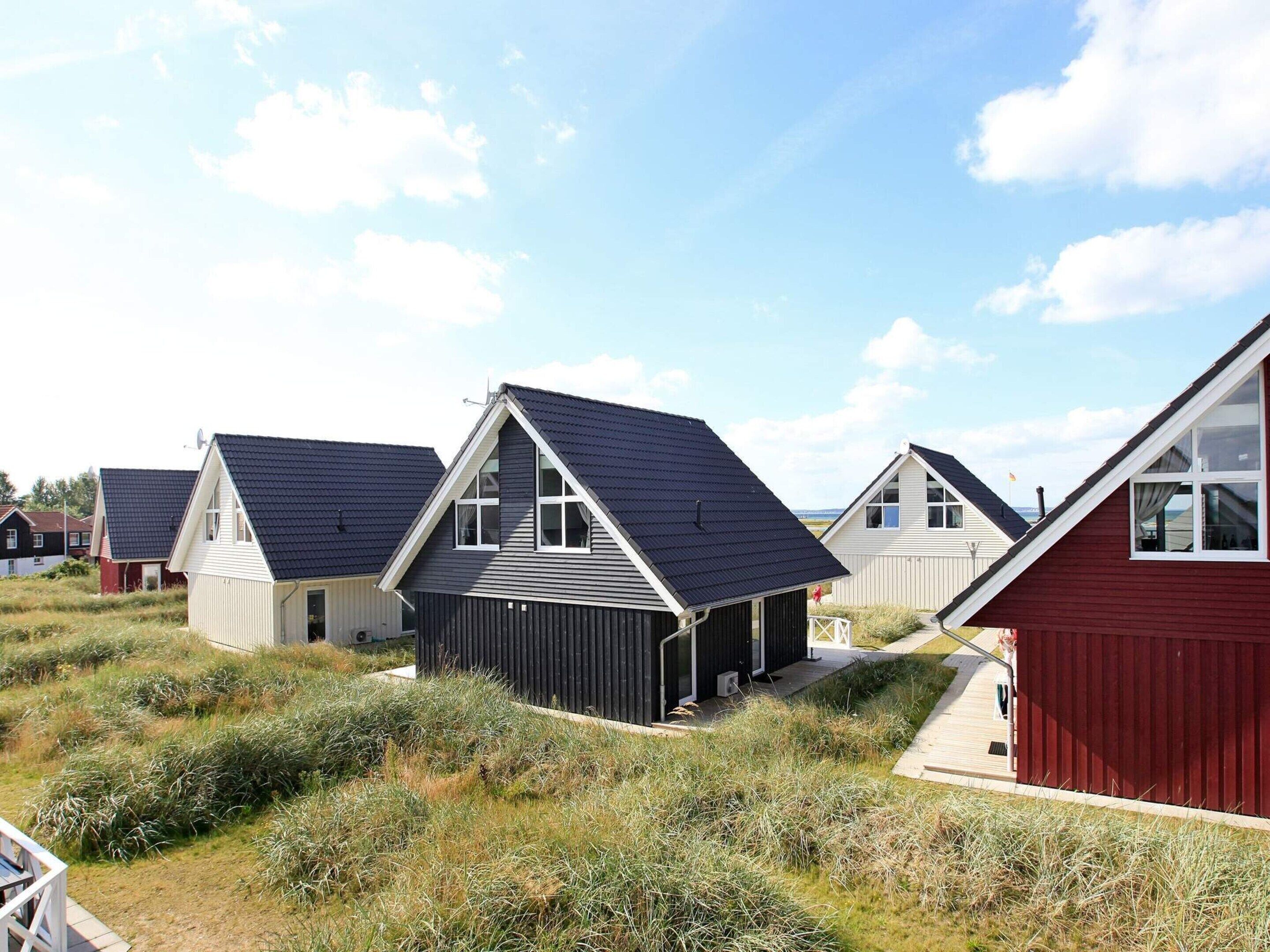 A row of modern, single-story houses with sloped roofs, surrounded by natural vegetation.