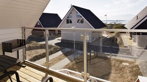 Een modern gebouw met een schuin dak, grote ramen en uitzicht op het strand.