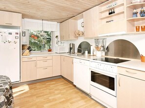 Eine moderne Küche mit Holzausstattung, einer Mikrowelle, einem Herd und einem Fenster mit Blick auf Bäume.