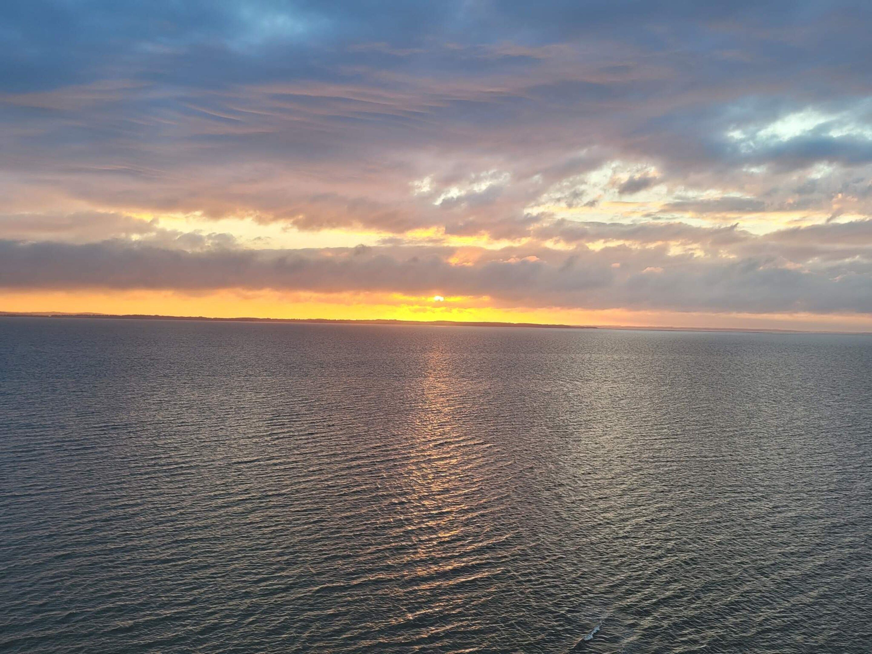 A calm sea at sunset with a clear horizon.