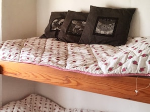 Un lit avec une couvre-lit à motifs floraux, une tête de lit en bois et deux oreillers foncés.