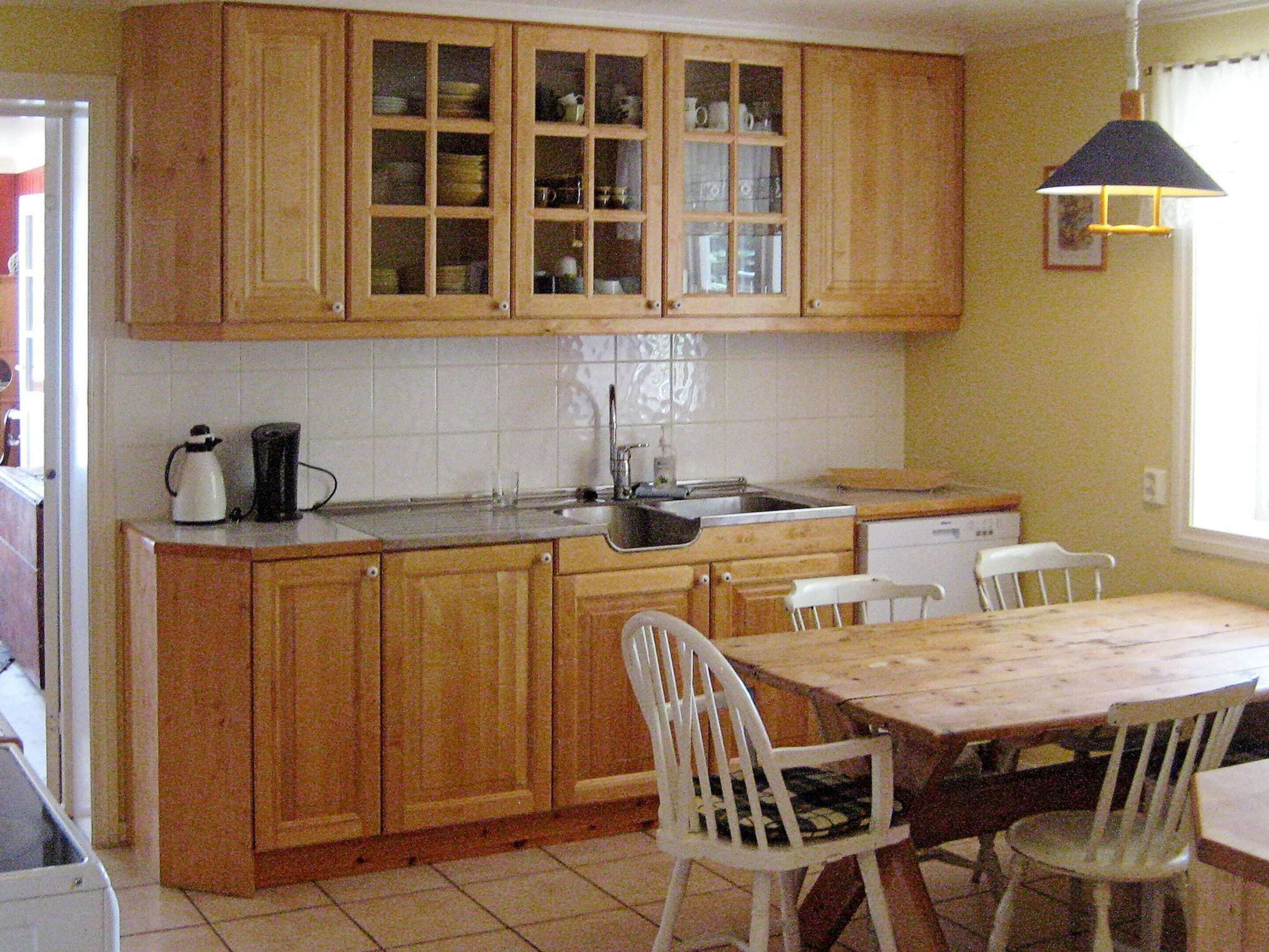 A kitchen with wooden cabinets, a sink, and a dining table with chairs.