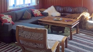 A cozy living room with a leather sofa, patterned armchair, and a wooden coffee table.