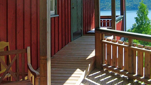 A wooden porch with a view of a lake and forest.
