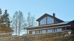 A modern two-story house with a stone retaining wall and a large window. - 6 Person Holiday Home in Blaksæter (Stryn)