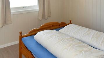 A single bed with a wooden headboard, a blue mattress cover, and white bedding.