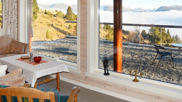 A room with a dining table and chairs, large windows with a view of a mountainous landscape. - 6 Person Holiday Home in Blaksæter (Stryn)