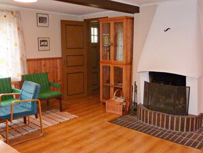 A living room with a fireplace, wooden flooring, and green upholstered chairs. - 6 Person Holiday Home in Paulistrom (Pauliström)