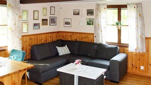 A cozy living room with a dark gray sectional sofa, a white coffee table, and a wooden dining table. - 6 Person Holiday Home in Paulistrom (Pauliström)