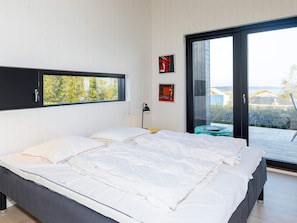 Quarto moderno com uma cama grande, janela com vista e porta de vidro deslizante para área externa.