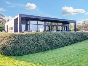 A modern house with a large glass facade, a flat roof, and a well-maintained hedge in front. - Simplistic Holiday Home in LÃ¸gstrup near Sea (Logstrup)