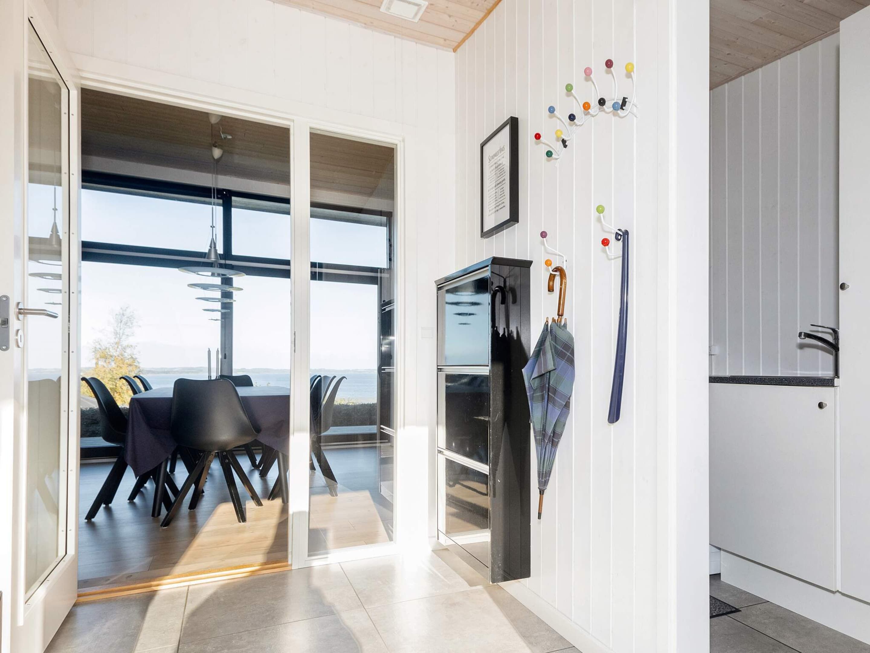 Une cuisine moderne dotée d’un réfrigérateur encastré, d’un coin repas avec une table et des chaises, et offrant une vue sur l’extérieur grâce à une porte vitrée.