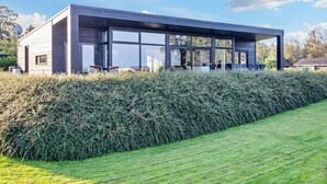 A modern house with a large glass facade, a flat roof, and a well-maintained hedge in the foreground. - Simplistic Holiday Home in LÃ¸gstrup near Sea (Logstrup)