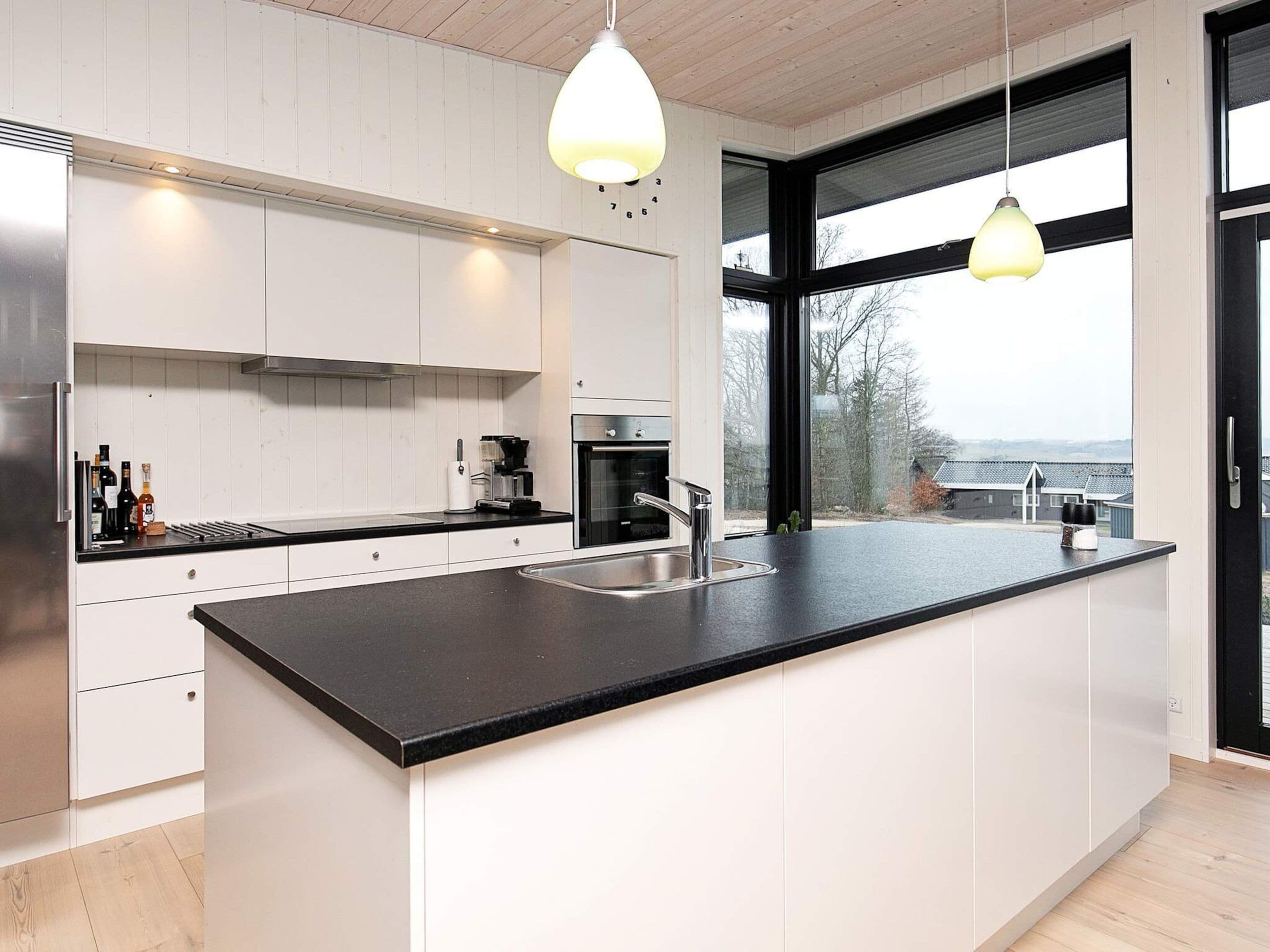 A modern kitchen with a large island, stainless steel appliances, and pendant lighting.