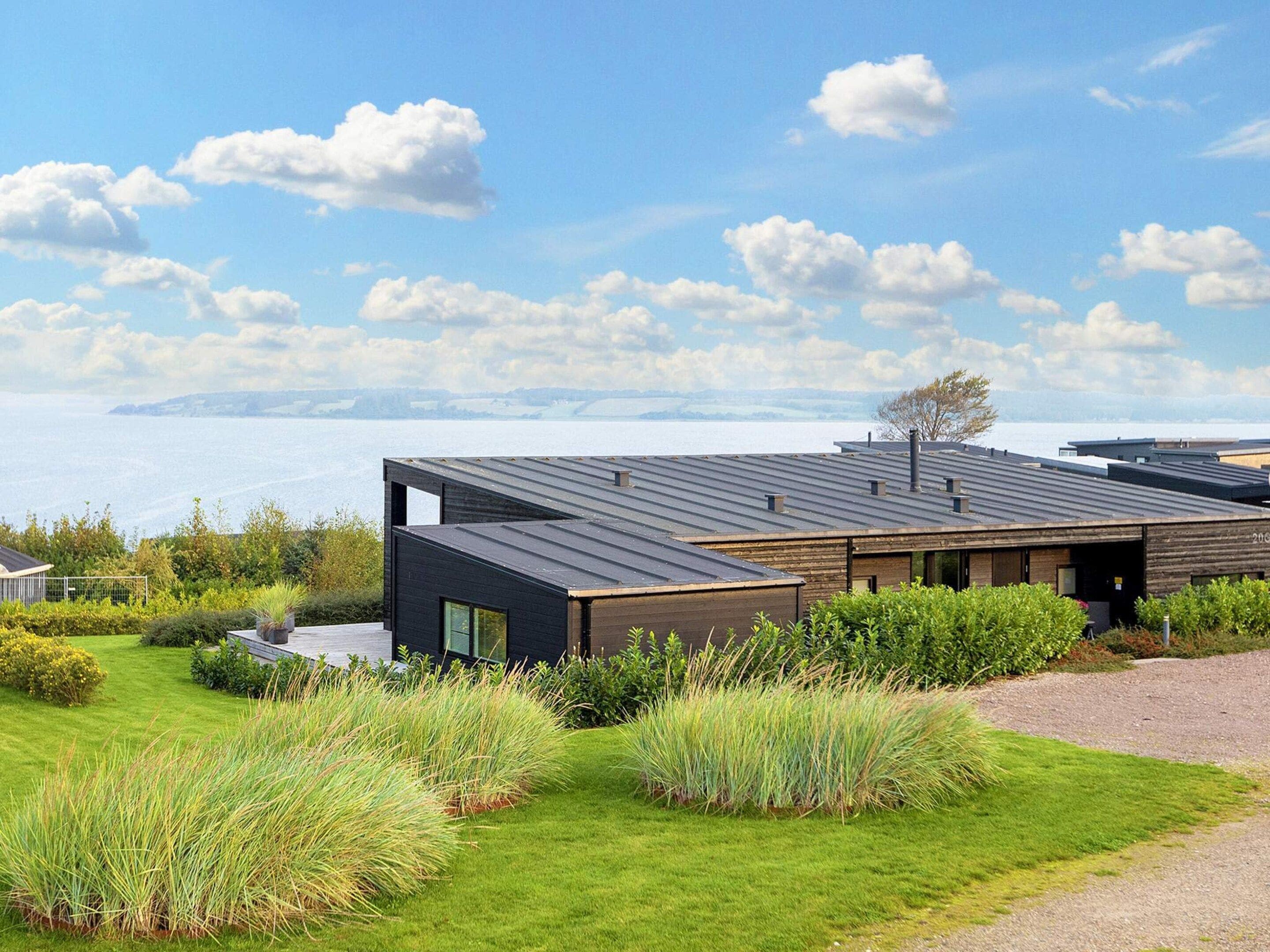 Une maison moderne avec un toit plat, de grandes fenêtres et une vue sur la mer.