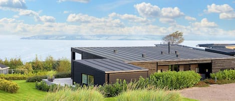 Una casa moderna con techo plano, ventanas amplias y vista al mar.