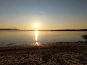 Um lago calmo ao pôr do sol, com céu claro.