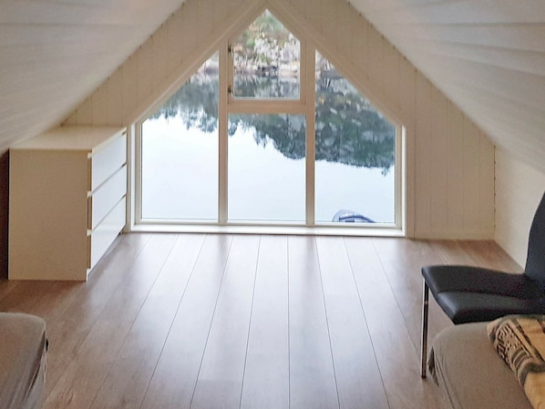 A high-ceilinged attic room with a large window overlooking a snowy landscape.