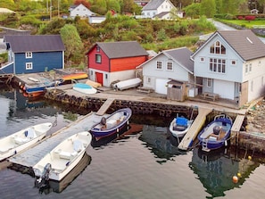 A harbor with boats docked, a red building, and houses in the background.