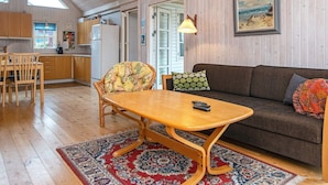 A cozy living room with a wooden dining table, a sofa, and a patterned rug. - 6 Person Holiday Home in Grenaa-by Traum (Grenaa)