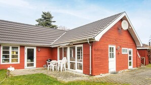 A red wooden house with a covered patio, a satellite dish, and a small outdoor seating area. - 6 Person Holiday Home in Grenaa-by Traum (Grenaa)