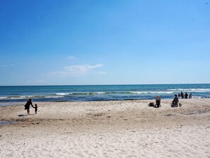 A beach with people, including a person in a wheelchair, and a clear sky. - 6 Person Holiday Home in Loderup (Loderup)