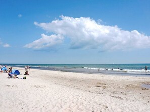 Une plage où des gens se prélassent au soleil et se baignent.