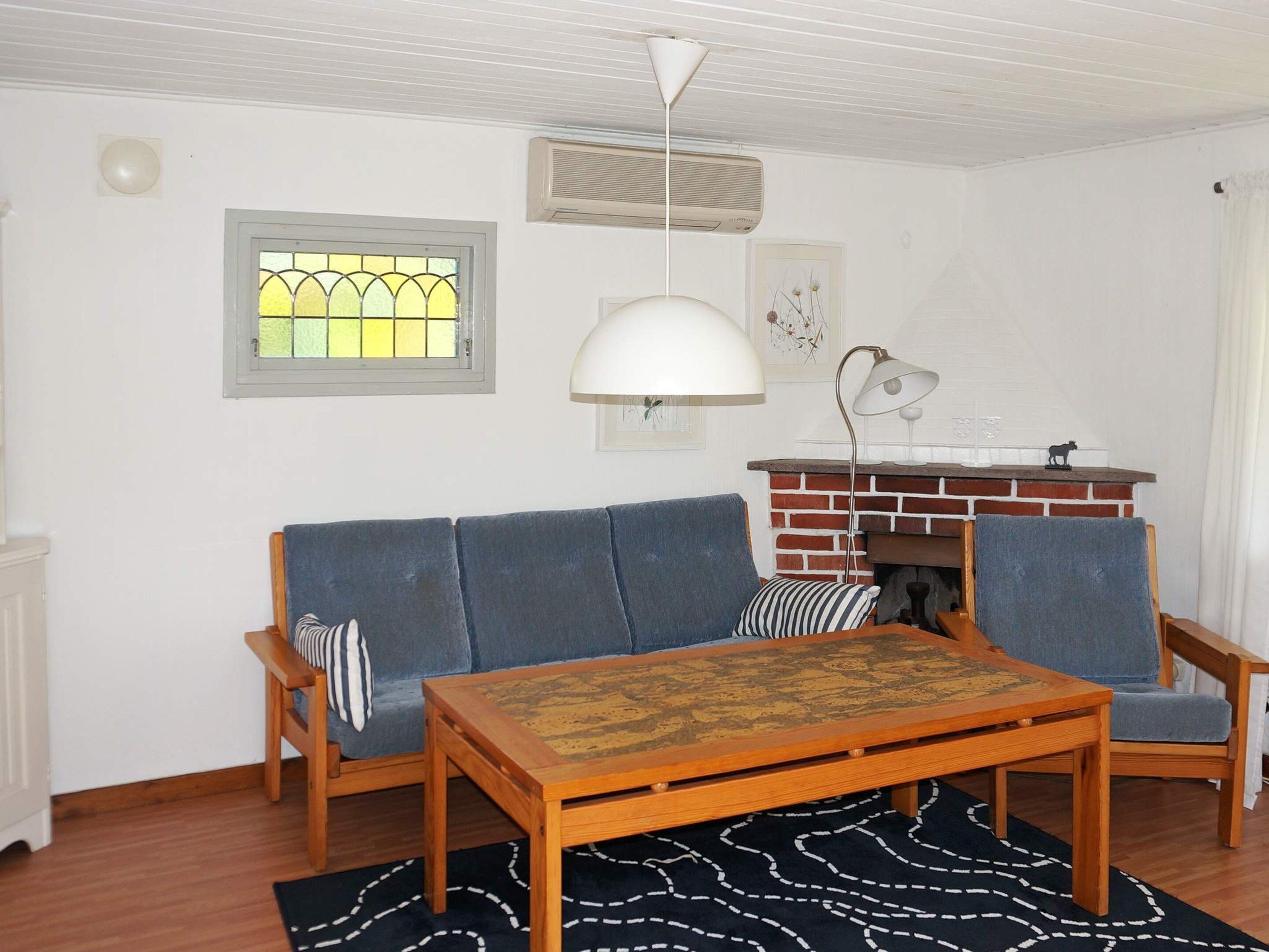 A living room with a sofa, two chairs, a coffee table, a fireplace, and a window with a stained glass design.