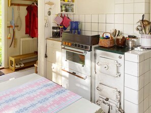 Uma cozinha com forno embutido, máquina de café e diversos utensílios de cozinha na bancada.