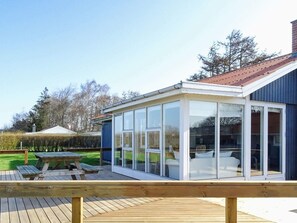 A modern house with a glass conservatory, a wooden deck, and a visible garden area. - Sunlit Holiday Home in Funen near Sea (Otterup)