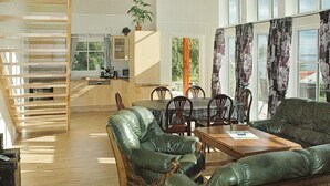 A spacious living area with a dining table, leather sofas, and a kitchen in the background. - Holiday Home in Vevang (Hustadvika)