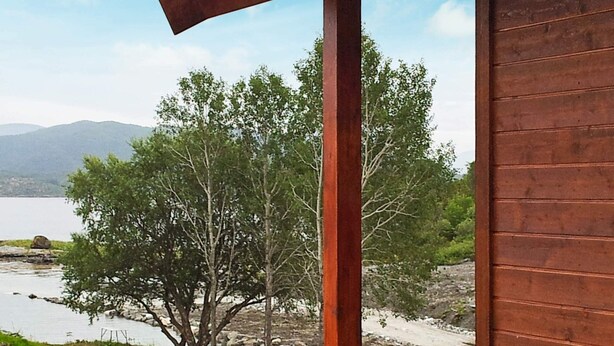 A wooden deck with a view of a lake and trees. - Holiday Home in Vevang (Hustadvika)