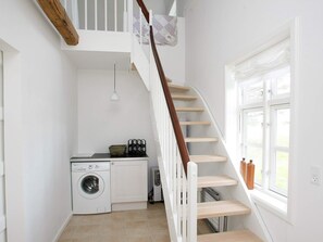 A laundry area with a washing machine, a dryer, and a wooden staircase leading to a loft. - 4 Star Holiday Home in Skagen (Skagen)