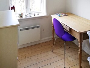 A room with a wooden desk, a purple chair, a radiator, and a window with a view of trees. - 4 Star Holiday Home in Skagen (Skagen)