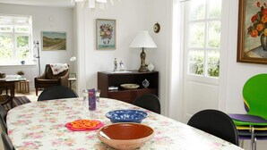Un comedor con mantel floral, un bol y un florero sobre la mesa.