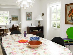 A dining area with a floral tablecloth, a bowl, and a vase on the table.