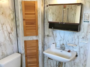 A bathroom with a toilet, wooden louvered doors, a sink, and a mirror with a towel rack. - 6 Person Holiday Home in Bakkasund (Austevoll)