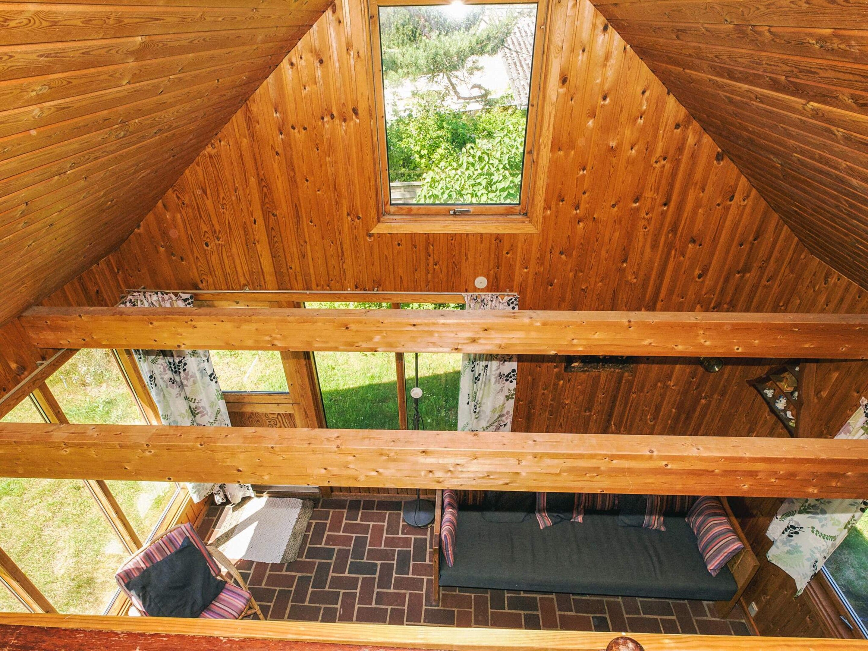 A wooden cabin with a sloped roof, a small window, and a brick floor.