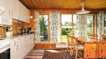 A kitchen with wooden cabinets, a stove, and a dining area with a table and chairs.