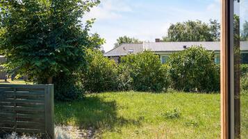A garden with a wooden fence, a tree, and a house with a tiled roof.