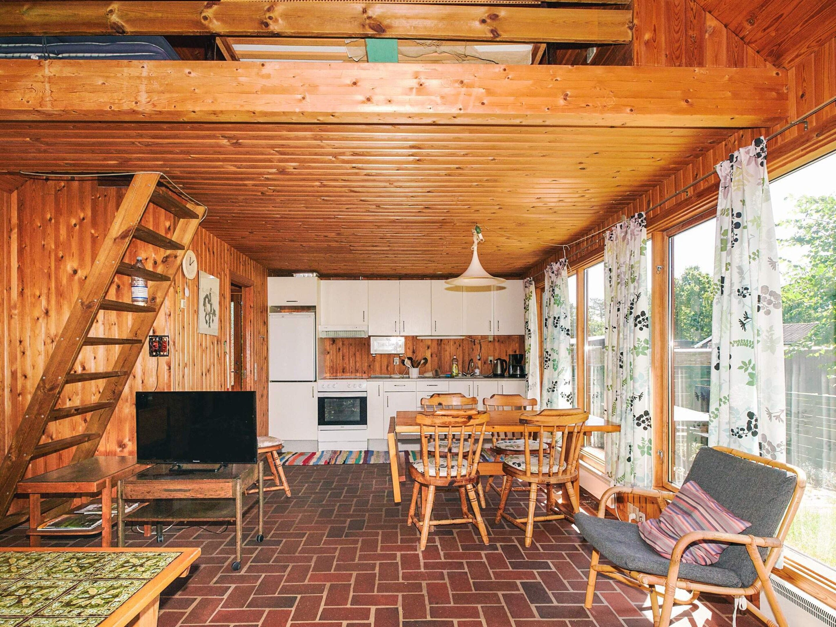 A wooden interior with a dining area, kitchen, and a TV.