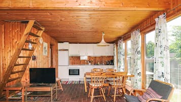 A wooden interior with a dining area, kitchen, and a TV.